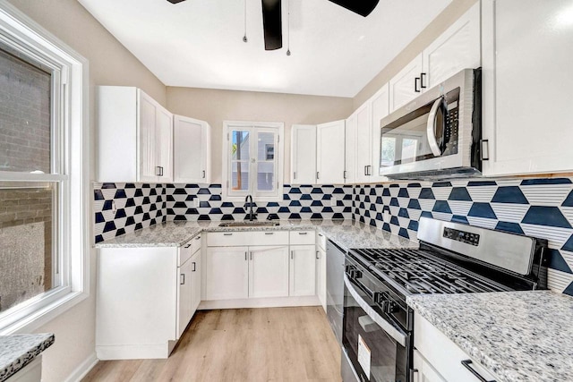 kitchen featuring a sink, white cabinets, stainless steel appliances, and light wood-style flooring