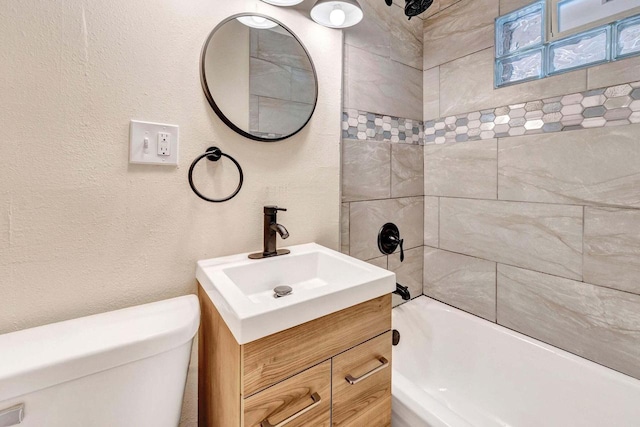 bathroom featuring toilet, a textured wall, shower / bathing tub combination, and vanity