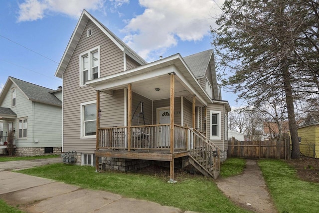 view of front of home featuring roof with shingles, fence, and covered porch