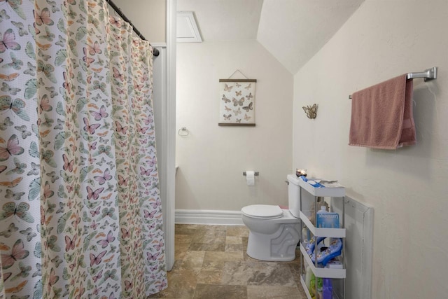 bathroom featuring stone finish floor, baseboards, toilet, lofted ceiling, and a shower with shower curtain