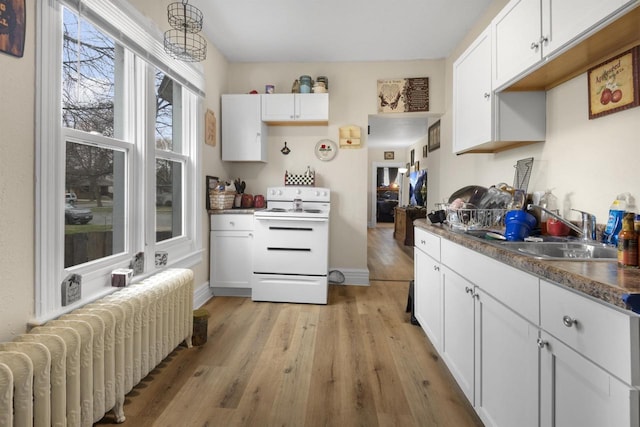 kitchen featuring electric range, a sink, white cabinets, radiator, and light wood-style flooring