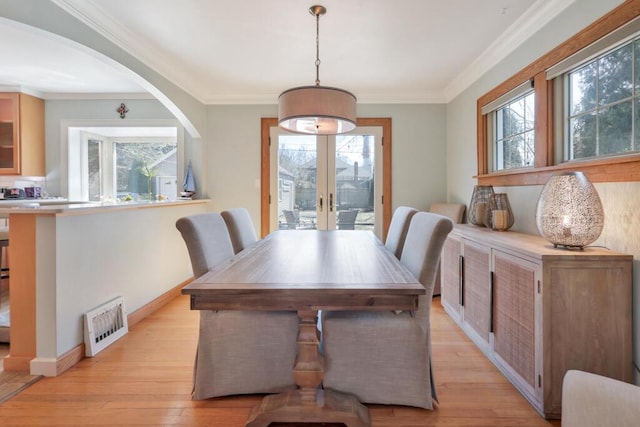 1517 Torrison Dr, Manitowoc, WI 54220 - dining space featuring light wood-style floors, french doors, arched walkways, crown molding, and baseboards