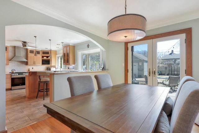 1517 Torrison Dr, Manitowoc, WI 54220 - dining space featuring plenty of natural light, french doors, light wood-style floors, crown molding, and arched walkways