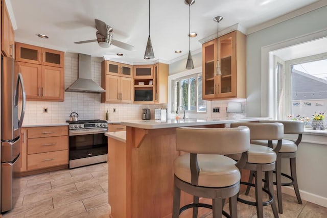 1517 Torrison Dr, Manitowoc, WI 54220 - kitchen featuring appliances with stainless steel finishes, wall chimney range hood, a breakfast bar area, decorative backsplash, and ceiling fan