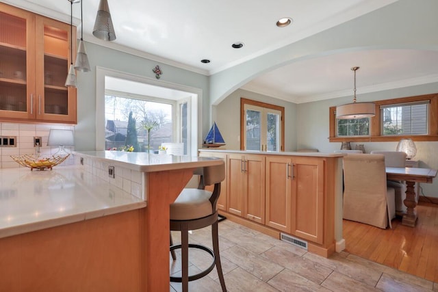 1517 Torrison Dr, Manitowoc, WI 54220 - kitchen featuring arched walkways, backsplash, healthy amount of natural light, light countertops, and crown molding
