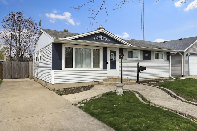 view of front of property featuring an attached garage, a shingled roof, fence, and a front yard