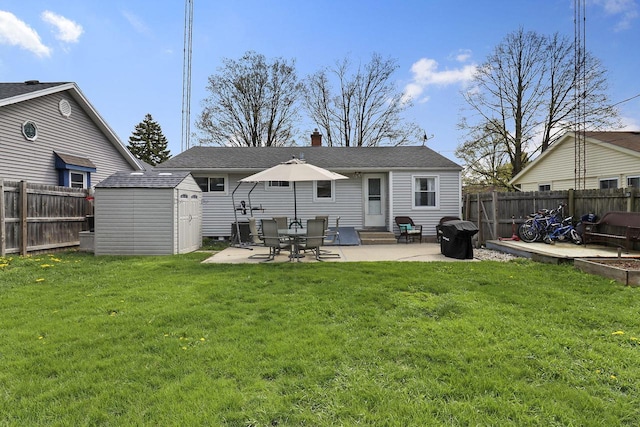 back of house featuring a storage unit, a fenced backyard, an outbuilding, a lawn, and a patio