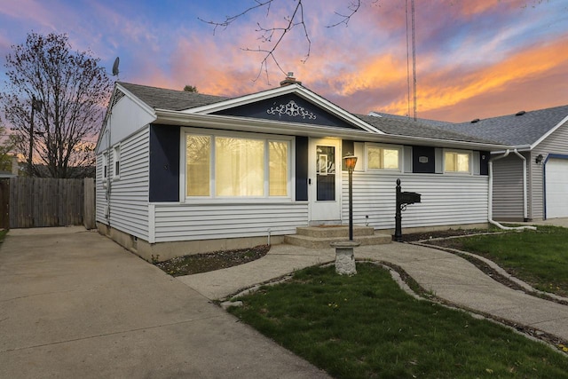 bungalow with fence, an attached garage, and driveway