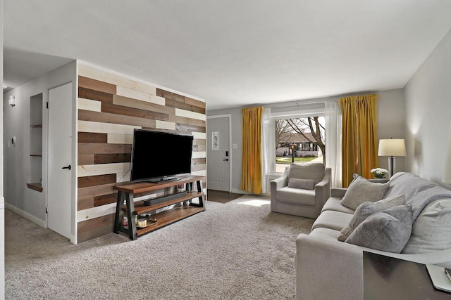 carpeted living area featuring baseboards and wood walls