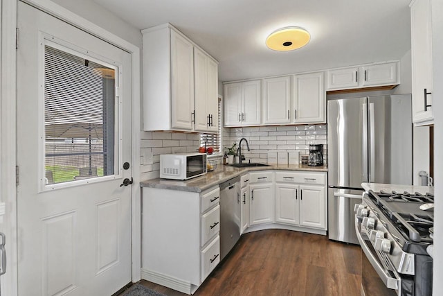 kitchen featuring decorative backsplash, dark wood-style flooring, white cabinets, a sink, and stainless steel appliances