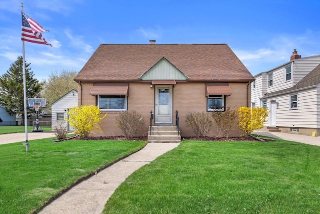 view of front of home with brick siding, a shingled roof, and a front lawn