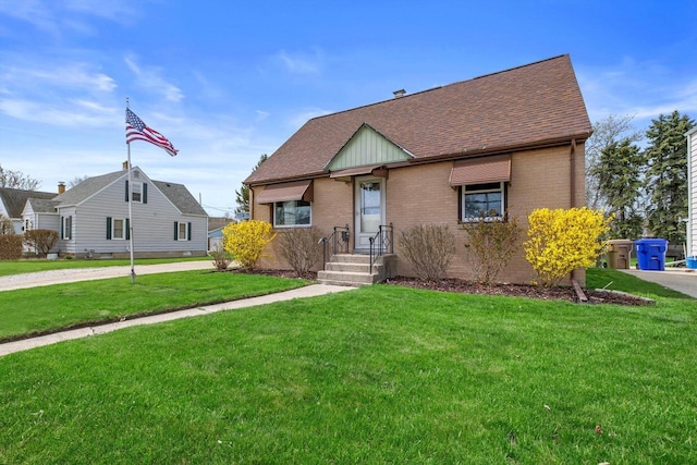 view of front of home featuring brick siding, a shingled roof, and a front yard