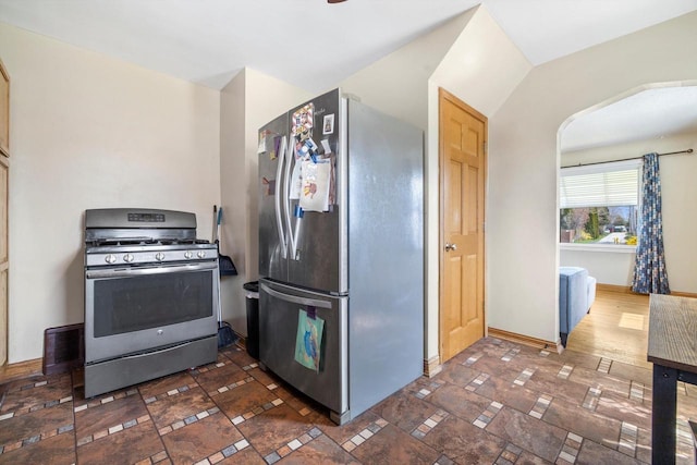 kitchen featuring baseboards, arched walkways, appliances with stainless steel finishes, and visible vents