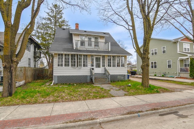 view of front of property with fence, a balcony, a chimney, and entry steps