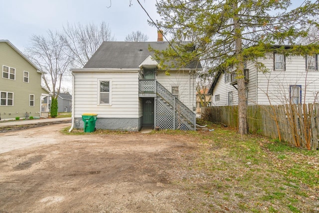 back of house with roof with shingles, fence, and a chimney