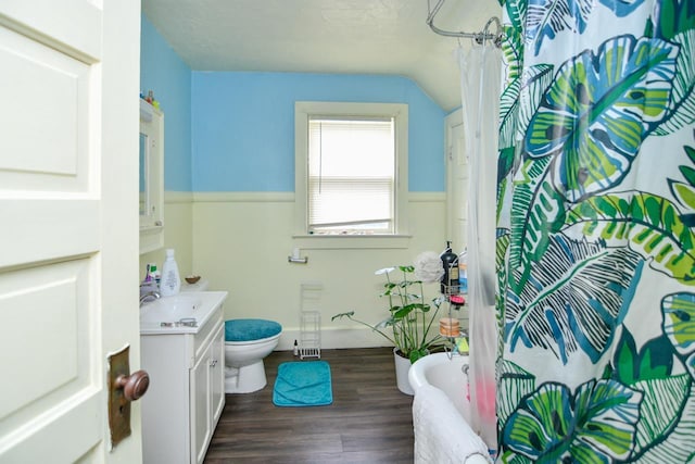 full bathroom with a bathtub, wood finished floors, vanity, toilet, and lofted ceiling
