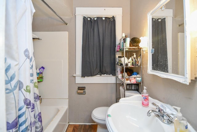 full bathroom featuring wood finished floors, toilet, a sink, and shower / tub combo