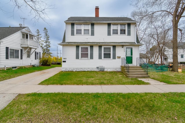 colonial inspired home featuring a front lawn, driveway, and a chimney