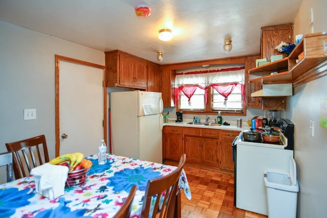 kitchen with light countertops, brown cabinetry, stove, freestanding refrigerator, and under cabinet range hood