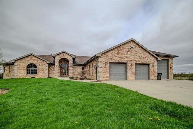 457 Union Rd, Brooklyn, WI 53521 - view of front of house featuring a front yard, concrete driveway, an attached garage, a shingled roof, and stone siding