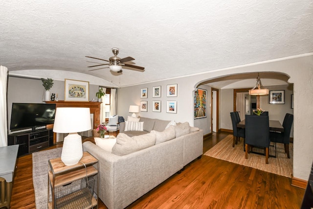 living room featuring baseboards, arched walkways, ceiling fan, and wood finished floors