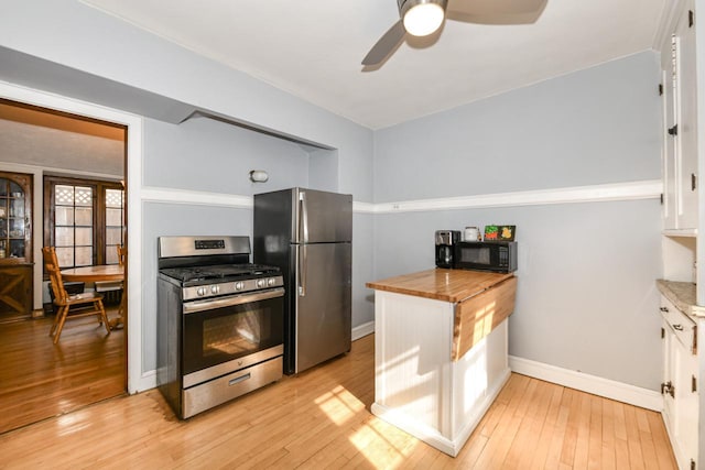 kitchen with light wood-style floors, a ceiling fan, stainless steel appliances, and butcher block counters