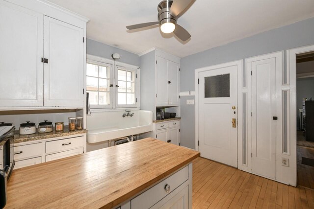 kitchen featuring ceiling fan, light wood-style flooring, butcher block counters, and white cabinets