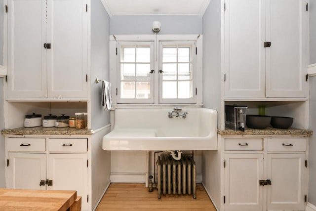 bathroom featuring baseboards, crown molding, wood finished floors, and radiator heating unit