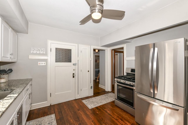 kitchen featuring ceiling fan, dark wood-style flooring, appliances with stainless steel finishes, light stone counters, and white cabinetry