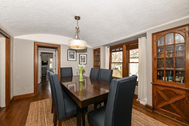 dining room with baseboards, a textured ceiling, dark wood-style flooring, and lofted ceiling
