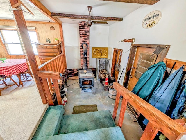 W7150 Maple Ridge Ln, Phillips, WI 54555 - stairs featuring a wood stove, wood walls, beam ceiling, a ceiling fan, and concrete floors