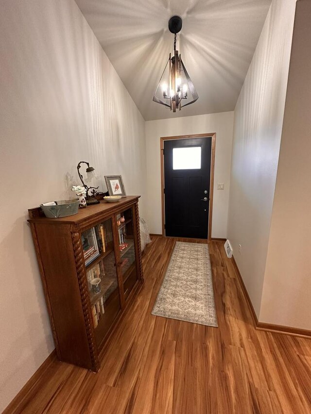 entrance foyer featuring an inviting chandelier, baseboards, and wood finished floors
