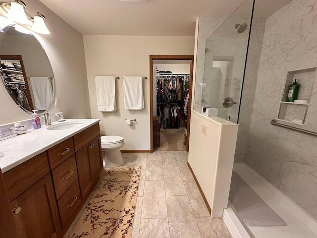 bathroom featuring toilet, walk in shower, a spacious closet, and vanity