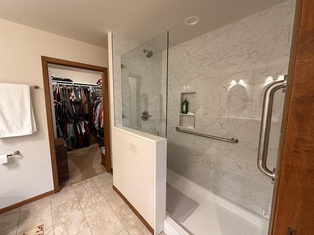 full bath featuring a marble finish shower, baseboards, and a spacious closet