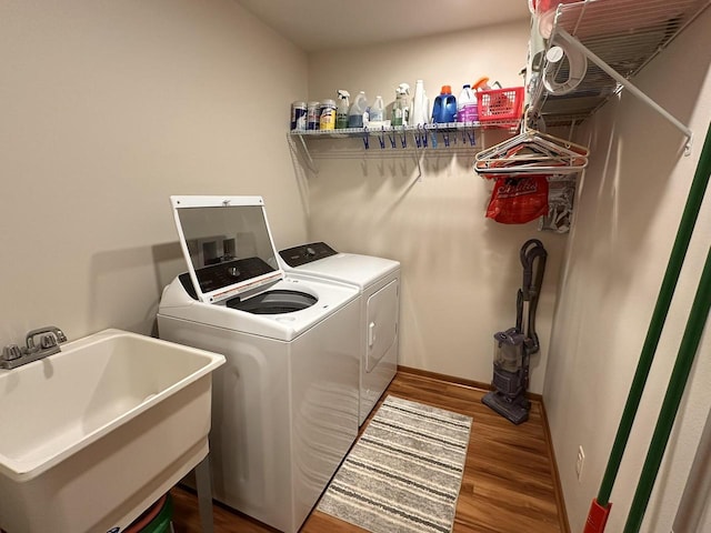 washroom featuring separate washer and dryer, laundry area, a sink, and wood finished floors