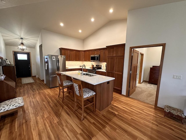 kitchen with a breakfast bar area, appliances with stainless steel finishes, a sink, and light wood-style floors
