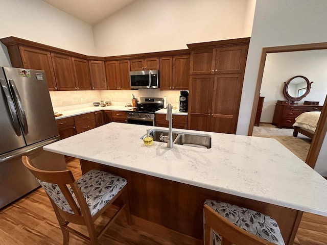 kitchen featuring high vaulted ceiling, appliances with stainless steel finishes, a sink, and tasteful backsplash