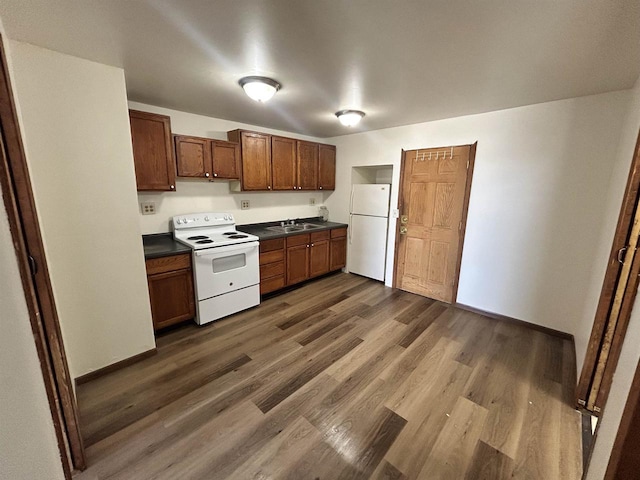 201-207 S Main St, Jefferson, WI 53549 - kitchen with dark countertops, a sink, baseboards, white appliances, and dark wood-type flooring