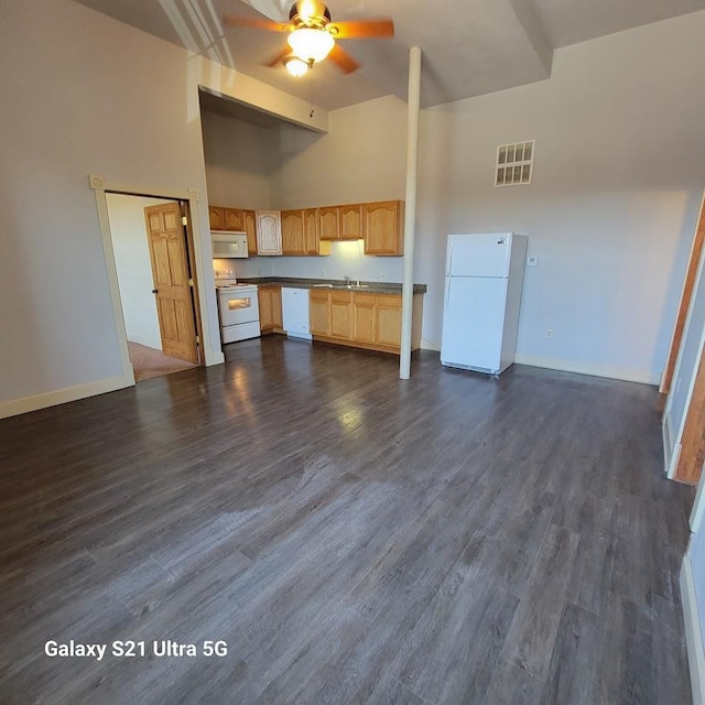 201-207 S Main St, Jefferson, WI 53549 - unfurnished living room featuring visible vents, a towering ceiling, baseboards, dark wood-style floors, and a ceiling fan