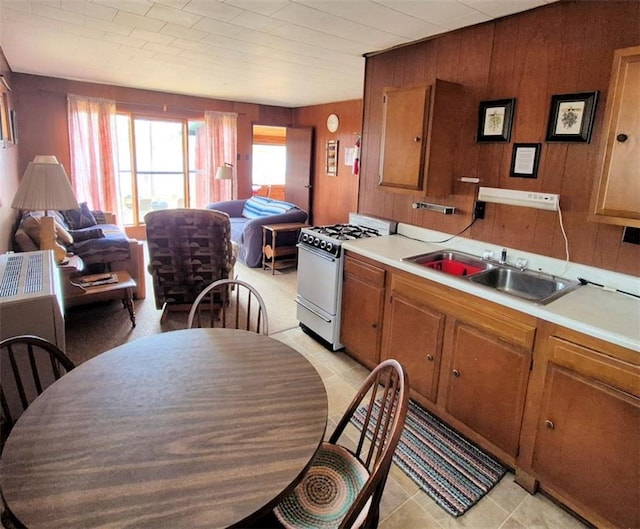 kitchen with a sink, brown cabinets, white gas stove, and light countertops