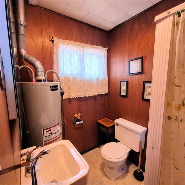 bathroom featuring wooden walls, toilet, a sink, and water heater