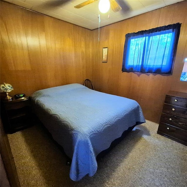 bedroom with carpet floors, a ceiling fan, and wood walls