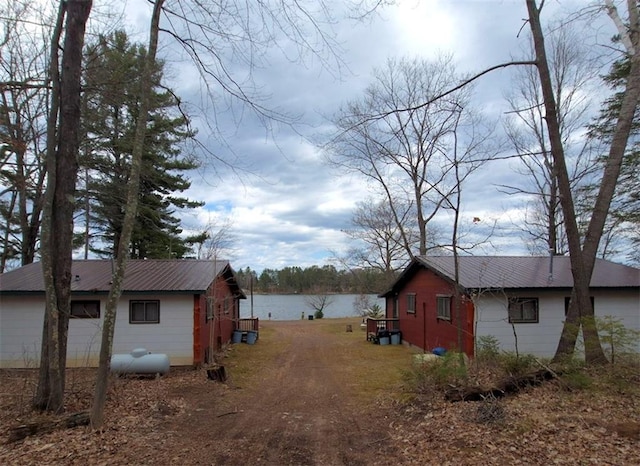 view of side of home featuring a water view, an outbuilding, and metal roof