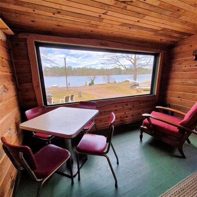 interior space with wooden walls, wood ceiling, a water view, and a wealth of natural light