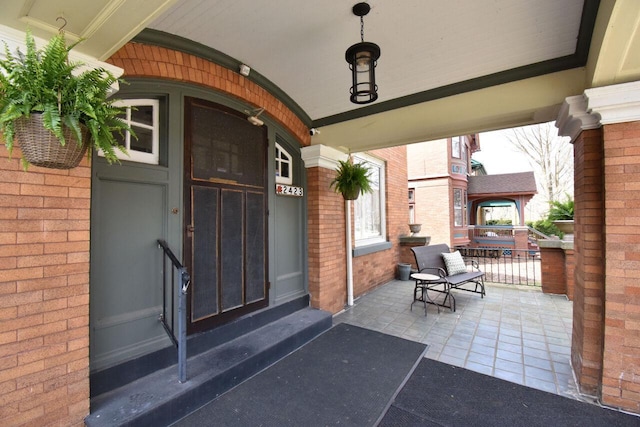 entrance to property featuring brick siding and covered porch