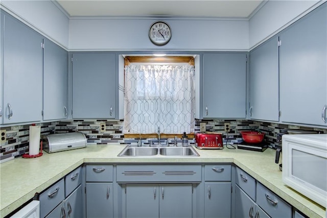 kitchen featuring light countertops, a sink, and white microwave