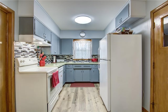 kitchen with decorative backsplash, light wood-type flooring, a sink, light countertops, and white appliances
