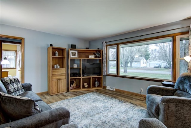 living room with baseboards, visible vents, and wood finished floors