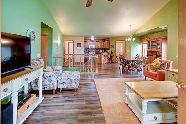 living room featuring ceiling fan with notable chandelier, wood finished floors, and high vaulted ceiling