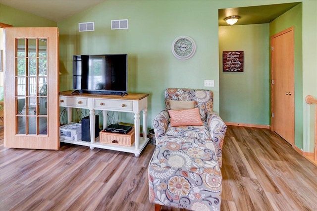 living room featuring visible vents, wood finished floors, and vaulted ceiling